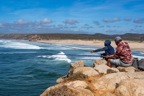 Anglers on the cliffs at the viewpoint above Praia da Bordeira beach, near Carrapateira, popular