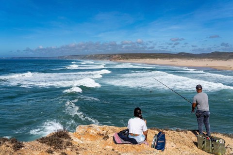Anglers on the cliffs at the viewpoint above Praia da Bordeira beach, near Carrapateira, popular