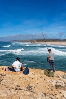 Anglers on the cliffs at the viewpoint above Praia da Bordeira beach, near Carrapateira, popular