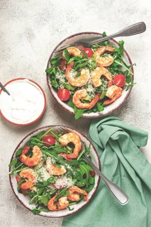 Two bowls of shrimp salad, arugula and cherry tomatoes, with parmesan cheese, healthy food