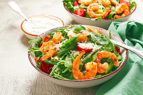 Two bowls of shrimp salad, arugula and cherry tomatoes, with parmesan cheese, healthy food