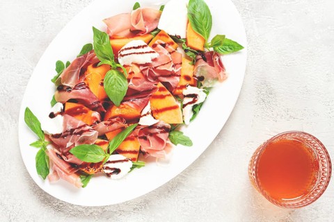 Salad with prosciutto and melon, with arugula and cheese, with balsamic sauce, natural light