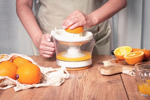 Preparation of freshly squeezed orange juice, using a juicer, in a cozy kitchen setting