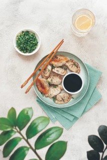 Gyoza Japanese dumplings, fried, with sauce, green onion, and sesame seeds, natural color, light
