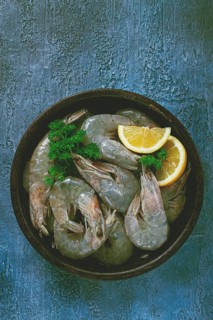 Fresh raw white-footed shrimp, tiger prawns vannamey, on a clay plate, with lemon and herbs, on a