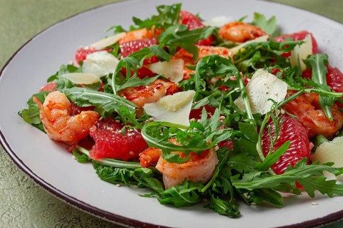 Fresh shrimp salad with arugula, grapefruit, and parmesan served in a bowl