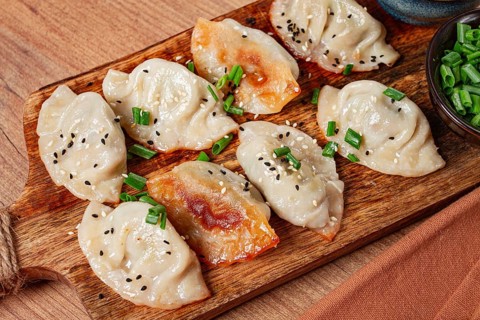 Gyoza Japanese dumplings, fried, with sauce, with green onion and sesame seeds, no people,