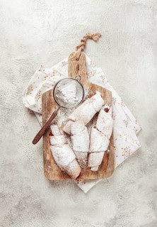 Bagels with filling, sweet pastries, sprinkled with powdered sugar, on a wooden board, dessert,