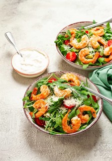 Two bowls of shrimp salad, arugula and cherry tomatoes, with parmesan cheese, healthy food