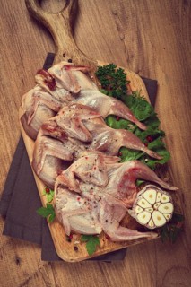 Raw quail meat, on a cutting board, with spices and herbs, top view