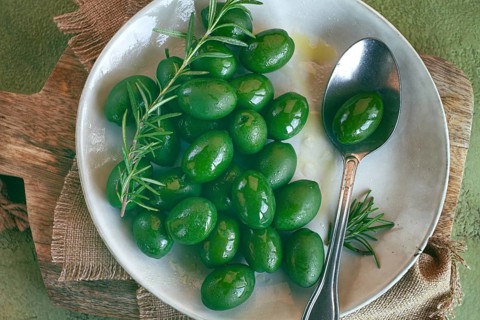 Chalkidiki olives, classic Greek green olive, on a plate, with a spoon, top view, no people
