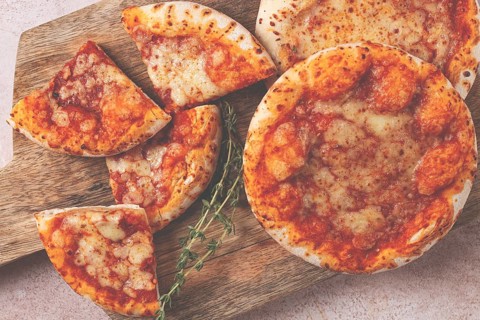 Four pizzetta Margaritas, on a cutting board, on a light gray surface, top view