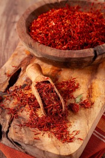 Spice saffron threads, in a wooden bowl, on a wooden table, top view, close-up