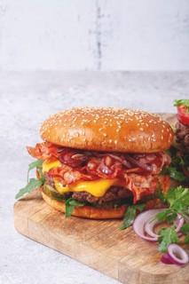 Burger with beef and bacon, with arugula and caramelized onions, pickles, sauce, homemade, no