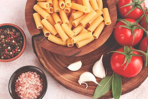 Pasta ingredients spread out, on a wooden surface, with tomatoes and spices, ready to cook, there