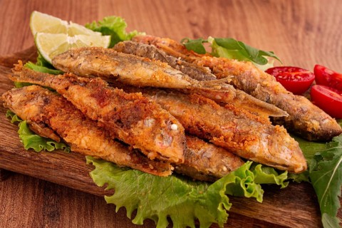 Fried crispy red mullet fish, on a wooden chopping board, with lime, no people