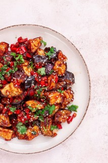 Fried eggplant, Chinese style, in sweet and sour sauce, with pepper and sesame seeds. on a white