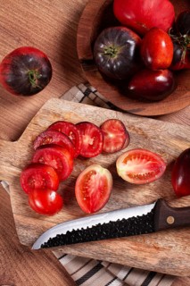 Sliced tomatoes, Black Beauty variety, on a cutting board, top view, on the kitchen table