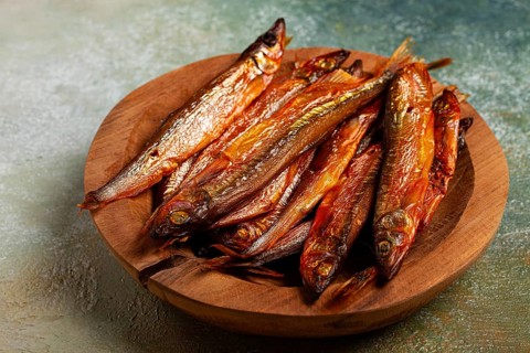 Cold smoked capelin, on a wooden bowl, top view, no people