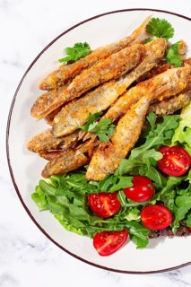 Fried crispy mullet fish, with fresh salad, on a plate with lime, no people