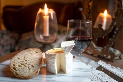 Chaource cheese presented sliced with bread and red wine in warm candlelight, typical of the