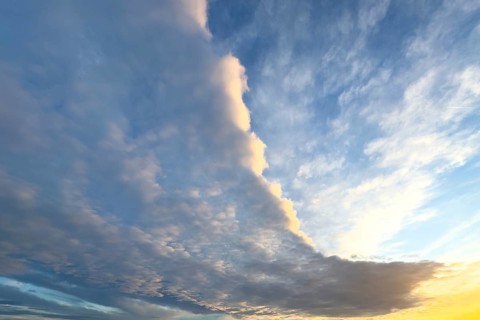 Cloud front with grey stratocumulus below right left and bright altocumulus clouds above
