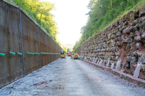 Machines on a construction site between steep walls overhung by trees, Hermann Hessebahn