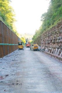 Construction site with heavy machinery on a stony road between steep embankments, Hermann Hessebahn