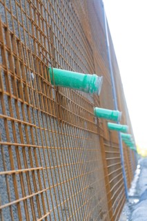 Side view of a construction wall with metal mesh and pipework, Hermann Hessebahn construction site,