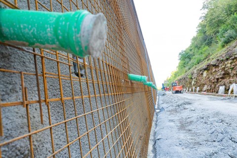 Close-up of a construction wall with metal mesh and green pipes, Hermann Hessebahn construction