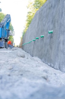 Large concrete wall and blue excavator on a gravel road, Hermann Hessebahn construction site, Calw,