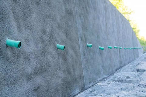 A row of green pipes protrudes from a reinforced concrete wall on a construction site, Hermann