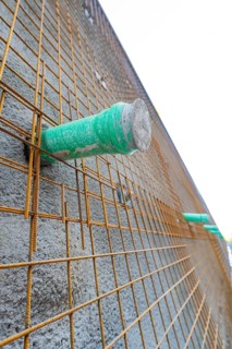 Close-up of a concrete wall with wire mesh and green pipes, Hermann Hessebahn construction site,