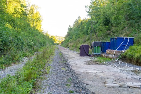 Gravel path with containers and cables in a wooded area along the track, Hermann Hessebahn