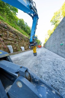 Close-up of crane arm on construction site, surrounded by concrete wall and trees, Hermann