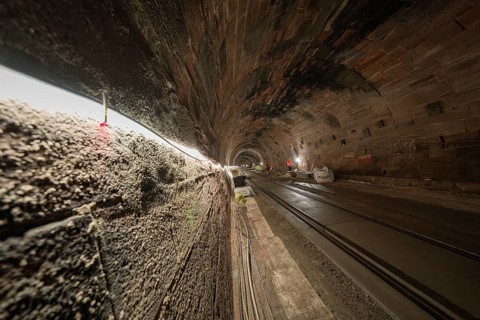 Tunnel with tracks and construction work, illuminated by line lights, construction of the Hermann