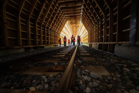 People in safety clothing standing in an illuminated wooden tunnel, construction of the Hermann