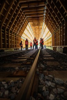 Groups of workers in a wooden railway tunnel, illuminated from the inside, construction of the