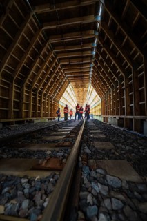 Group of employees in an illuminated wooden tunnel on railway tracks, construction of the Hermann