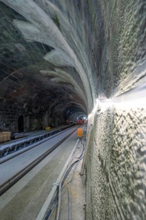 Unfinished tunnelling with exposed cables and rails in a shady environment, construction of the