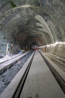 An unfinished tunnel with rails, in a dark, rough construction site environment, construction of