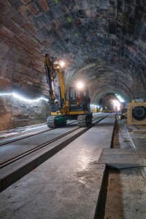An excavator in an illuminated tunnel on rails, with a depth of perspective in the scene,