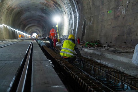 Construction workers in the tunnel working on the tracks. The scene is illuminated by strong light,