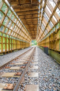 Empty wooden tunnel with view of green landscape through the transparent area, construction of the