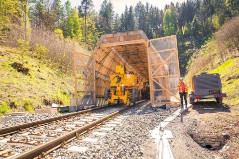 Machine and worker at the entrance to a tunnel in the forest, construction of the Hermann Hesse