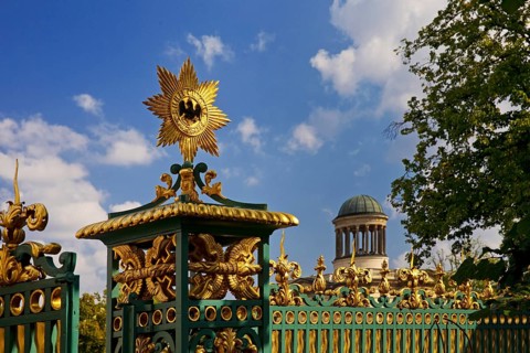 Golden star with black eagle on the fence of Charlottenburg Palace and dome of the Stüler Building,