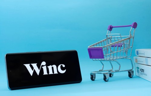 Dhaka, Bangladesh- 03 July 2025: Smartphone with Winc logo next to a small shopping cart and boxes