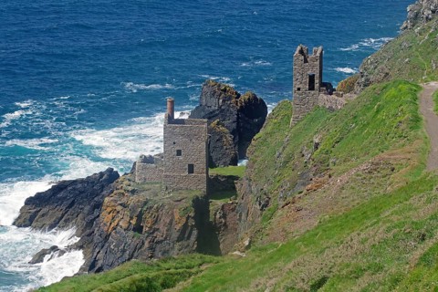 Historic ruins perched on a cliff, surrounded by rocky coastline and surging sea waves, engine room