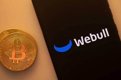 A Bitcoin coin next to a Webull logo on a black background