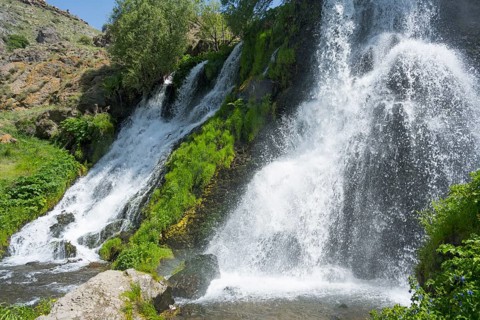 A rushing waterfall flows over moss-covered rocks in a green setting, Shaki Waterfall, Shaki,